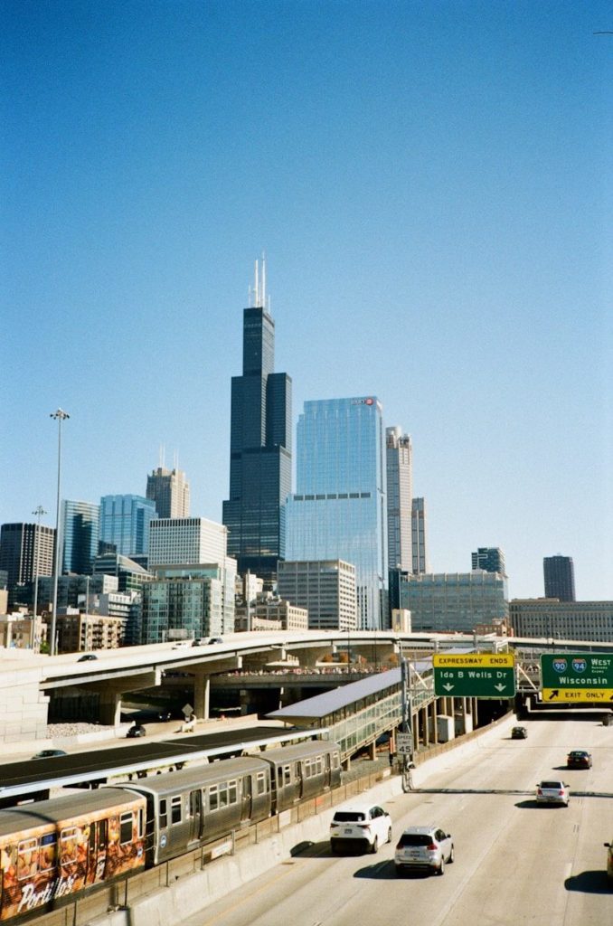 City skyline with skyscrapers, highway, and train.